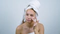 Amiable teenager wrapped in towels examining her face with acne