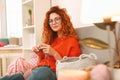 Amicable girl with ginger hair sitting near big window