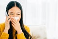 A sick woman calls doctor while blowing wiping nose sneezing on sofa