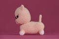 Cute little crocheted cat, handmade art. Amigurumi kitten doll on pink background. A soft DIY toy made of natural cotton Royalty Free Stock Photo