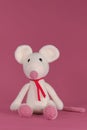 Amigurumi one white mouse with big ears and long nose on a pink background. A soft DIY toy made of natural cotton and Royalty Free Stock Photo