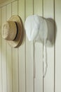 Amish bonnet and straw hat hanging on wall