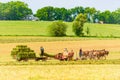 Amish man and woman baling hay in a field in Pennsylvania USA