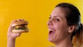 Charming young woman looking at a tasty beef burger in her hands and smiling joyfully. Royalty Free Stock Photo