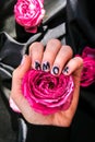 AMOR word on nails manicure hold Pink rose flower on black silk fabric. Minimal flat lay nature. Female hand. Love Royalty Free Stock Photo