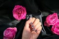 AMOR word on nails manicure hold Pink rose flower on black silk fabric. Minimal flat lay nature. Female hand. Love Royalty Free Stock Photo