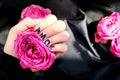 AMOR word on nails manicure hold Pink rose flower on black silk fabric. Minimal flat lay nature. Female hand. Love Royalty Free Stock Photo