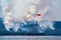 Amphibious airplane drops water on forest fire near the lake Royalty Free Stock Photo