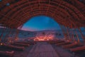 Amphitheater in a desert hosting a psychology conference, bioluminescent artifacts glowing under bamboo structures