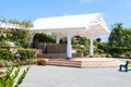 An amphitheater in the garden with a white wooden roof over the stage and colorful flowers with wooden benches and blue sky Royalty Free Stock Photo