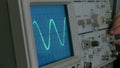 Amplitude diagram on the oscilloscope. A man presses the buttons on the device. The geometric line changes shape