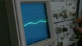 Amplitude diagram on the oscilloscope. A man presses the buttons on the device. The geometric line changes shape