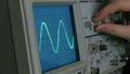 Amplitude Diagram on the oscilloscope. A man presses the buttons on the device. The geometric line changes shape