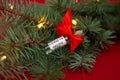 Ampoule of the COVID-19 coronavirus vaccine lies as a gift on branches of a Christmas tree with lights on red background