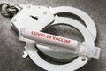 An ampoule with a covid-19 pandemic vaccine and handcuffs, a major plan. Concept on punishment for forgery of caronavirus vaccine