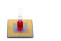 Ampoule filled with a red medical product stands on a cpu processor.
