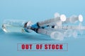 An ampoule with medicine and five syringes stuck in the bottle cap, on the background of the inscription: out of stock. The Royalty Free Stock Photo