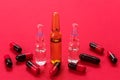 Ampoules for injections and many capsules on a red background. Copy space. Royalty Free Stock Photo