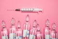 Ampoules and syringe on a pink background, the concept of cosmetic injections