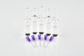 Ampoules and violet syringe needles on white background