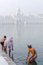 Amritsar, India - November 21, 2011: Sikh pilgrims bathe in the Amrit Sarovar Lake complex of the Golden Temple. The Golden Temple