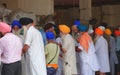 Amritsar, Punjab / India - 09.05.2019 : Sikh mans with colorful turbans washing dishes at the Langar of Golden Temple