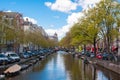 AMSTERDAM-APRIL 30: Amsterdam cityscape with row of cars, bikes and boats parked along the canal during the sunny day. Royalty Free Stock Photo