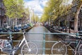 Amsterdam canal with bikes on the bridge and parked cars along the bank. Netherlands. Royalty Free Stock Photo