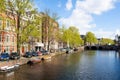Amsterdam canal with boats along the bank of the river in the spring. Netherlands.