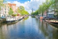 Amsterdam canal lined with traditional Dutch architecture of canal houses and houseboats moored along both sides