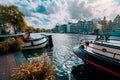 Amsterdam canal Singel with typical dutch houses and houseboats during sunny autumn day. Golden trees and amazing cloudscape.