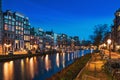 Amsterdam canal with typical dutch dancing houses at night with city lights reflections in water, Holland, Netherlands Royalty Free Stock Photo