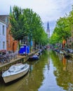 Amsterdam canal view with stationery boats, parked cycles and a monument in the distance