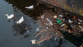 Amsterdam city trash and plastic bottles in water canal and white swans feed from garbage in river. Environment