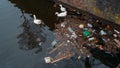 Amsterdam city trash and plastic bottles in water canal and white swans feed from garbage in river. Environment