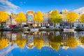 Amsterdam in the fall time. Capital of the Netherlands. View of old houses and the canal. Reflection on the surface of the water.