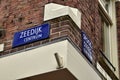 Amsterdam, Holland, August 2019. Blue signs of the streets of the historic center: zeedijk corner Spook steeg. Red brick wall