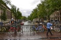 Amsterdam, Holland, August 2019. Typical view over a canal in the historic center. Rainy day. Colorful bikes parked on the railing Royalty Free Stock Photo