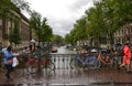 Amsterdam, Holland, August 2019. Typical view over a canal in the historic center. Rainy day. Colorful bikes parked on the railing Royalty Free Stock Photo