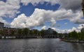 Amsterdam, Holland, August 2019. View of the Amstel River. On the shore boats house, behind the town. Blue sky with soft white Royalty Free Stock Photo