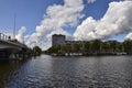 Amsterdam, Holland, August 2019. View of the Amstel River. On the shore boats house, behind the town. Blue sky with soft white