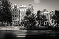 Amsterdam, Holland, the Netherlands - July 6 2020: 6 typical canal houses at a canal with moving trees and a kissing couple in