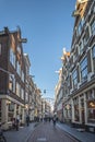 Amsterdam, narrow street, in the center. All day life with the shops people with shopping bags, bicycles, outdoor shopkeepers and Royalty Free Stock Photo