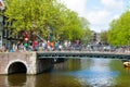 AMSTERDAM,NETHERLANDS-APRIL 27: Amsterdam canal with crowd of people on the bridge and bikes on King's Day in Amsterdam.