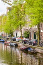 Amsterdam, Netherlands - April 27, 2019: Small boat on the canal in the city center of the Dutch capital. Parked cars by