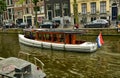 Amsterdam, Netherlands. August 2019. A boat along one of the canals of the red light district. Parked cars and bikes along the Royalty Free Stock Photo