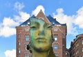 AMSTERDAM, NETHERLANDS. Cityscape with Modern green bronze sculpture of a head in the city center of Amsterdam with old