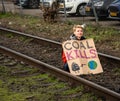 Young climate activist sitting on a rail track used for coal transport with a sign saying \