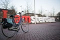 AMSTERDAM, THE NETHERLANDS - February, 17th, 2018: I Amsterdam sign placed in front of RAI Congress Center and a bicycle parked in