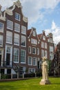 Garden of Begijnhof with ancient buildings and Christ statue. Famous medieval yard with sculpture of Jesus Christ in Amsterdam.